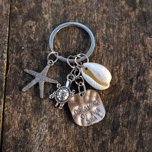 Keychain with starfish, turtle, and shell charm on a wooden surface