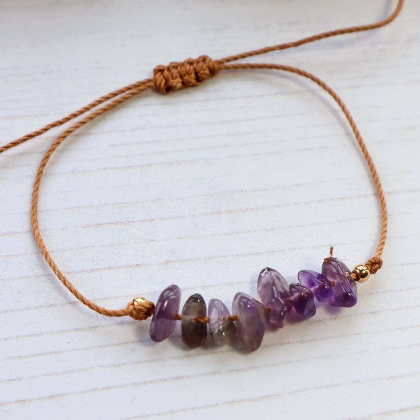 close up of purple amethyst chip bracelet on white wooden background