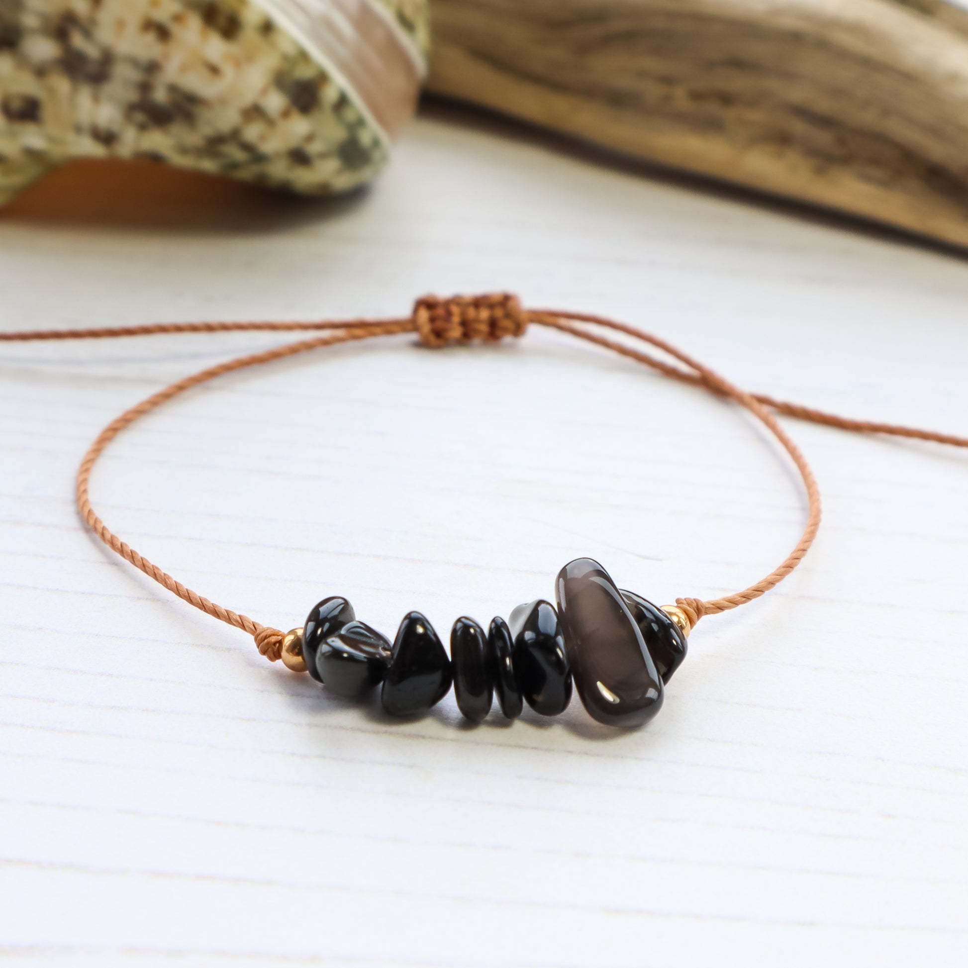 close up of Bracelet with black chip crystals on white wooden background with shells and driftwood