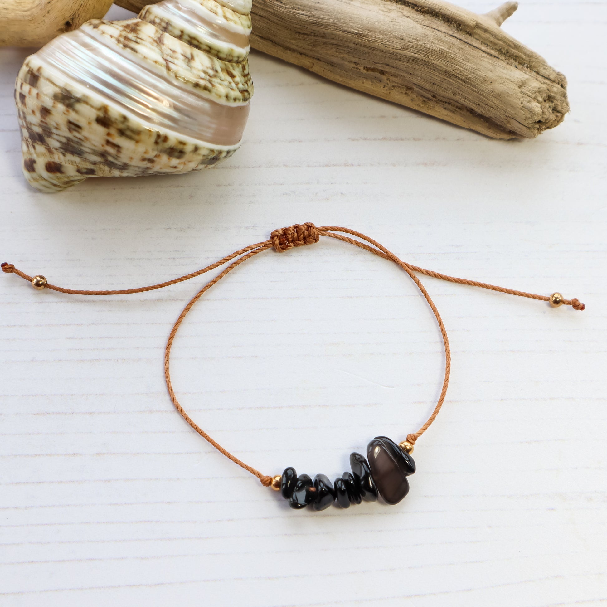 Bracelet with black chip crystals on white wooden background with shells and driftwood