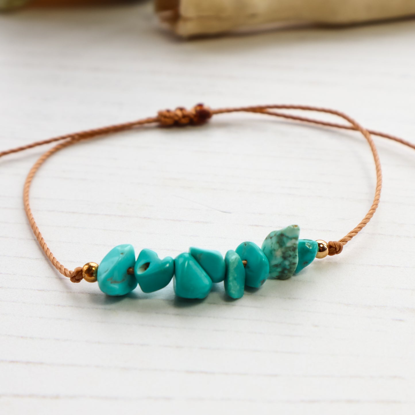 close up of Blue chips threaded on bracelet on white wooden background