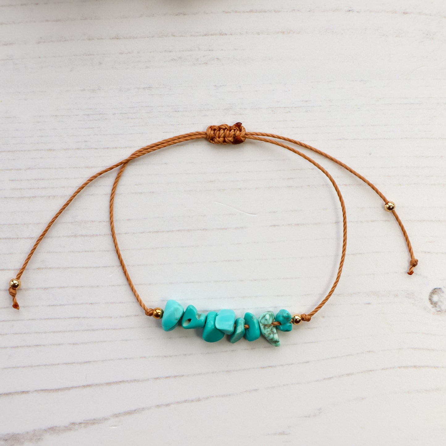 Blue chips threaded on bracelet on white wooden background