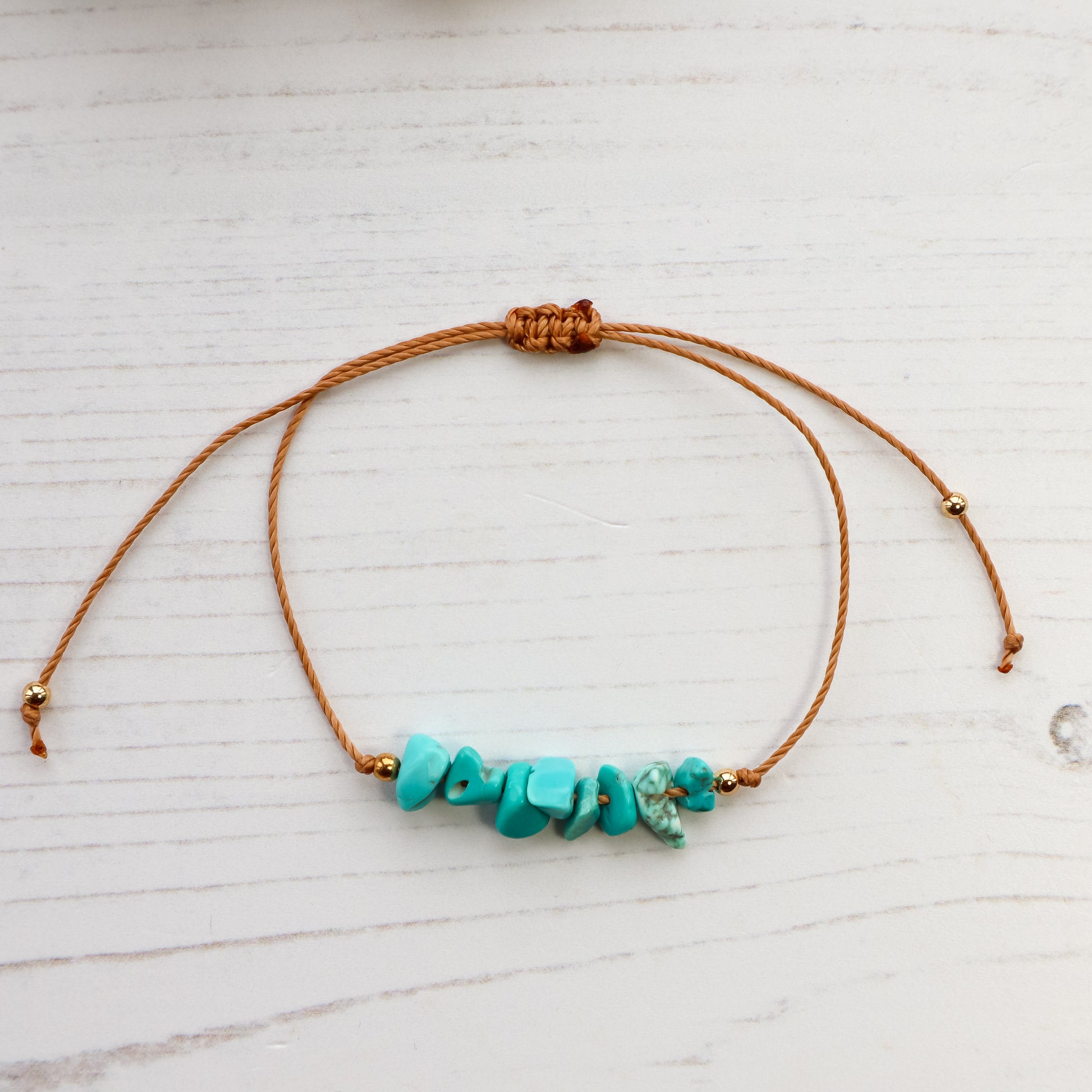 Blue chips threaded on bracelet on white wooden background