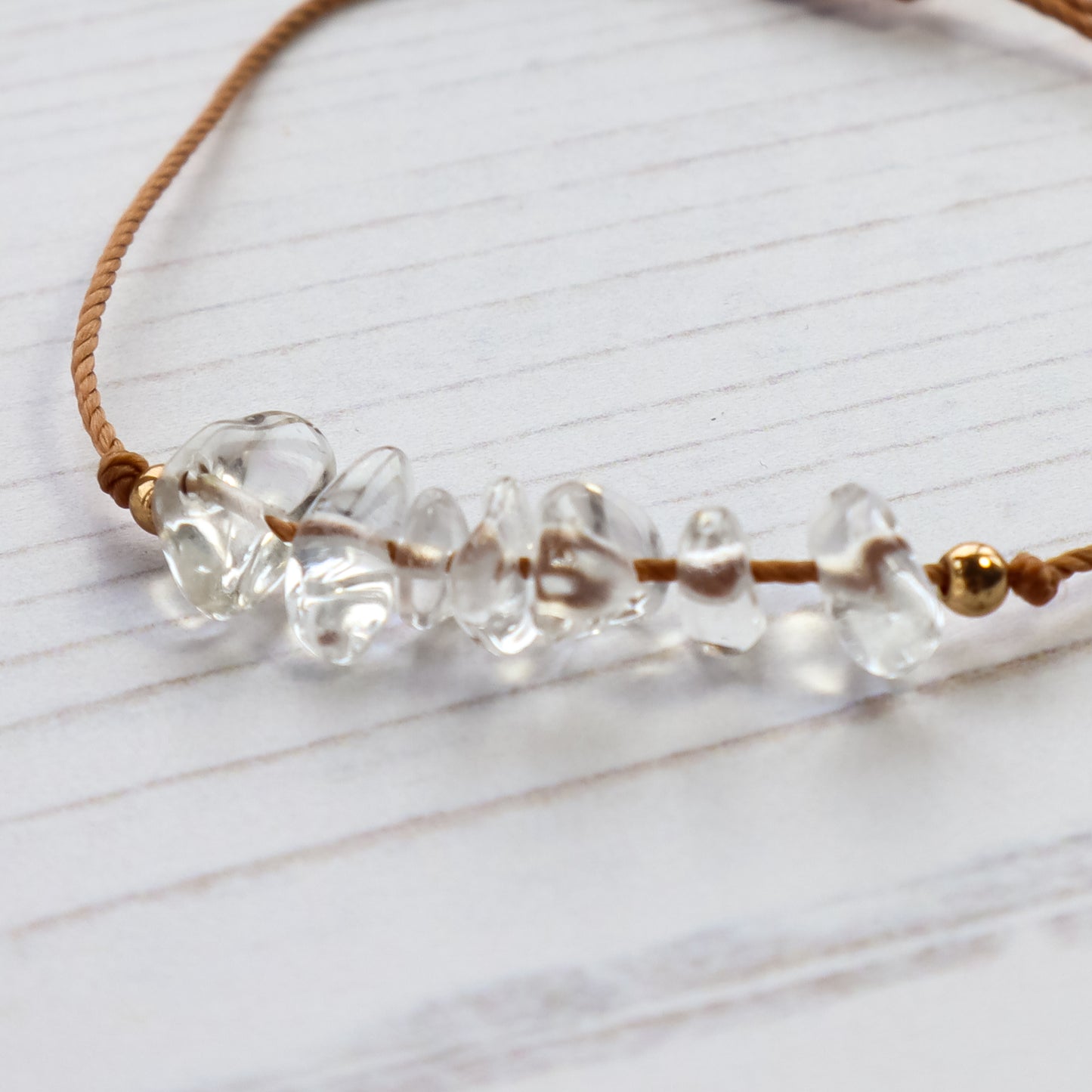 close up of clear quartz crystal chips threaded on brown cord