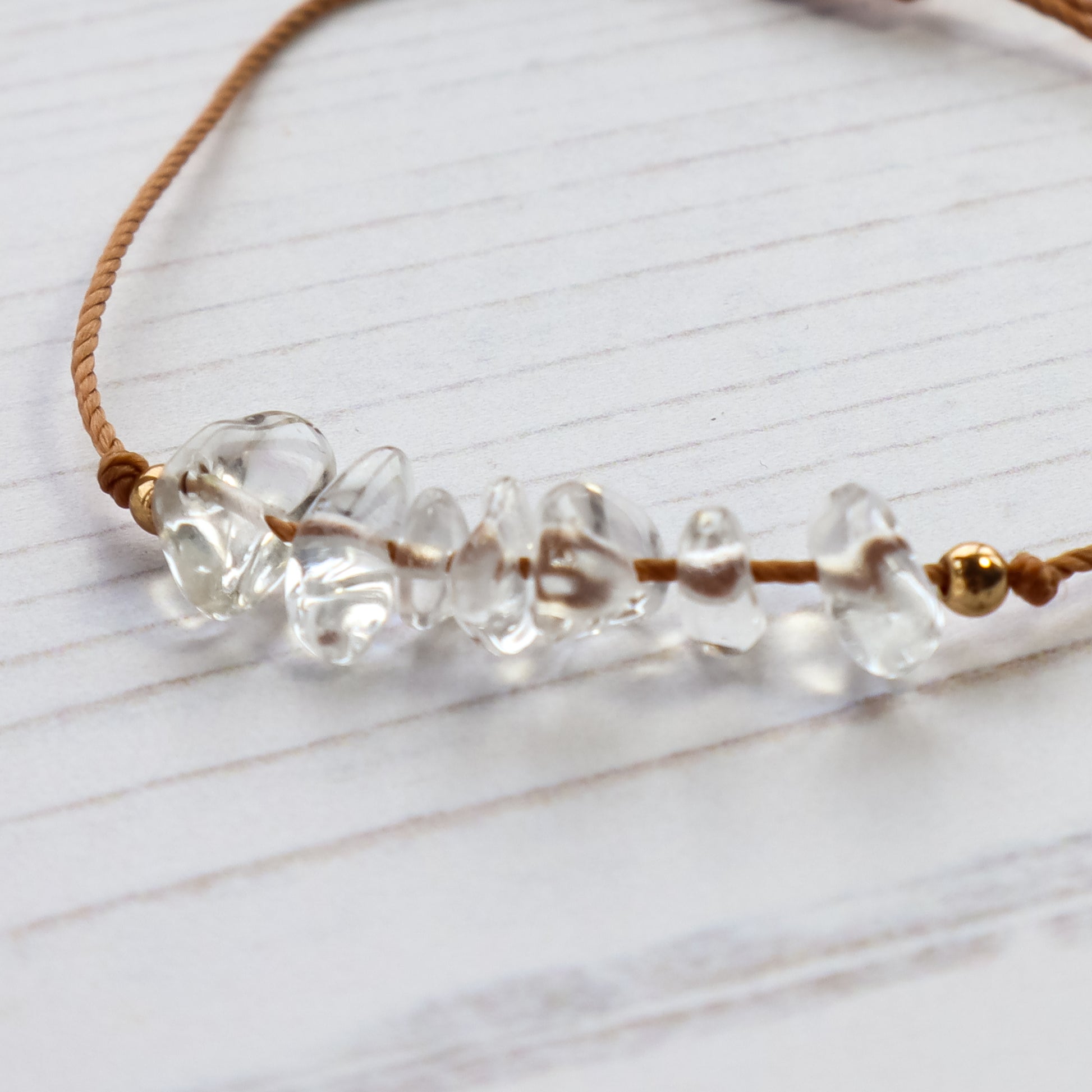 close up of clear quartz crystal chips threaded on brown cord