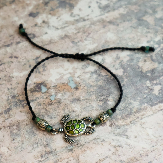 Bracelet with turtle charm on a textured surface