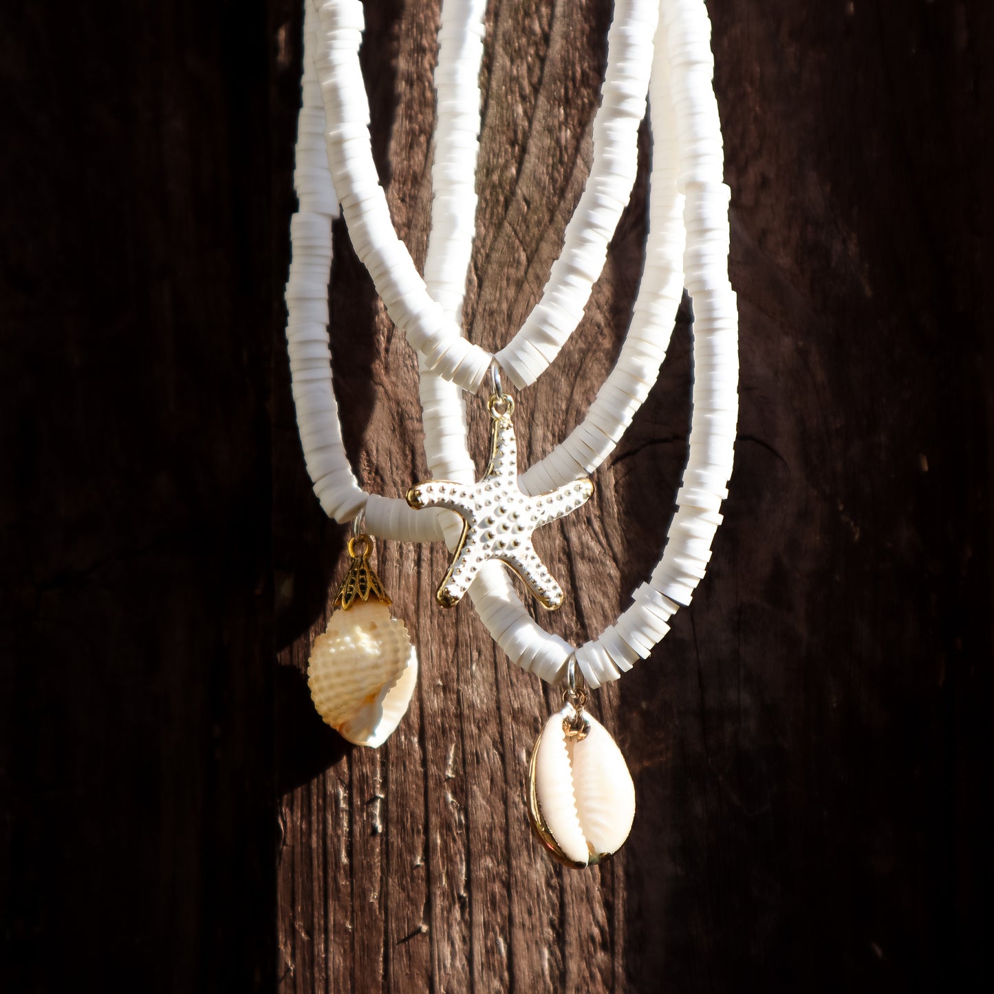 White beaded necklaces with starfish and shell pendants on a wooden surface