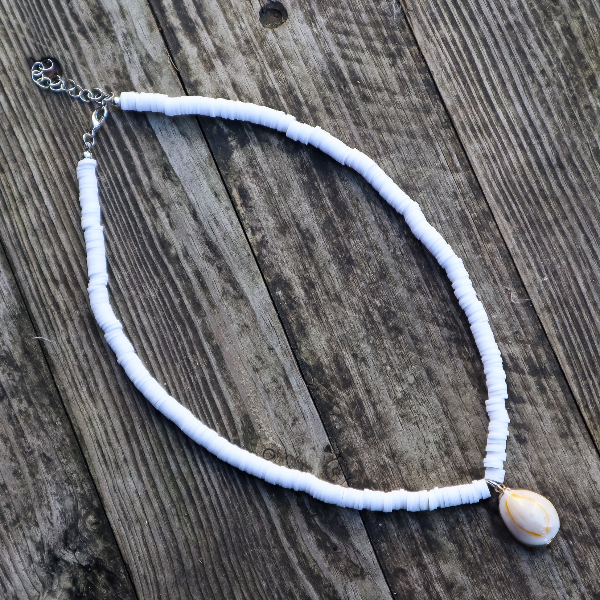 White necklace with a shell pendant on a wooden surface