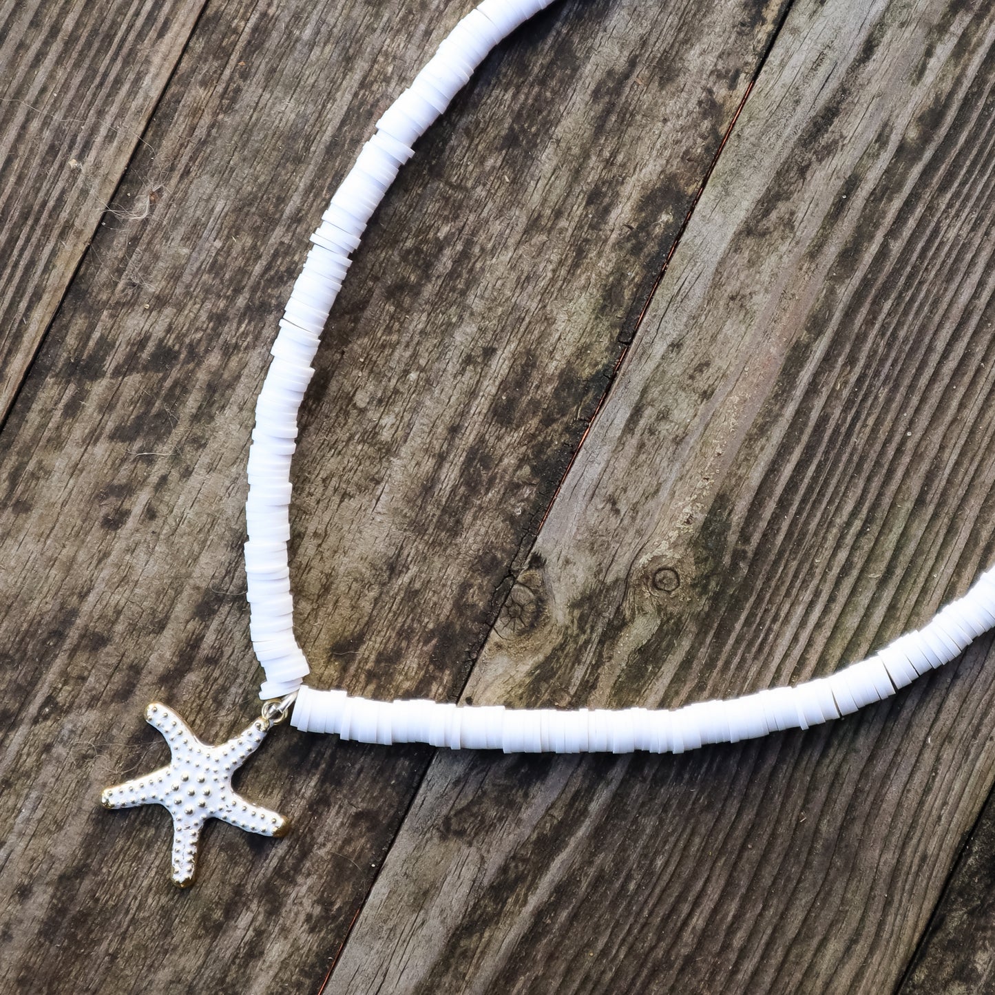 White beaded necklace with a starfish pendant on a wooden surface