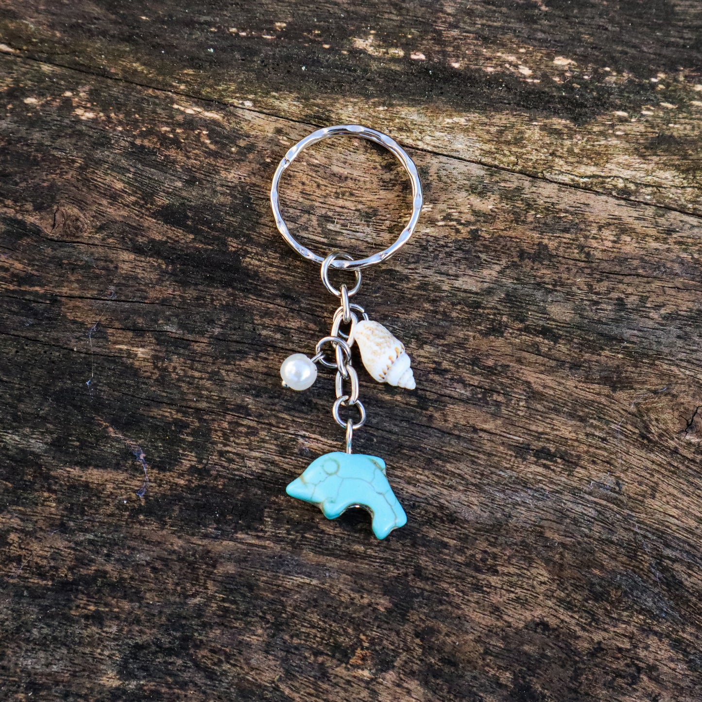Keychain with a turquoise bear charm and shell on a wooden surface