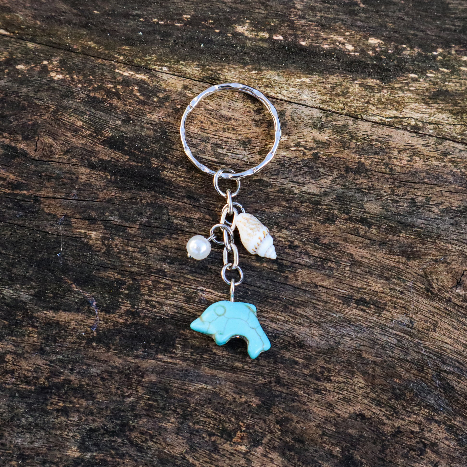 Keychain with a turquoise bear charm and shell on a wooden surface