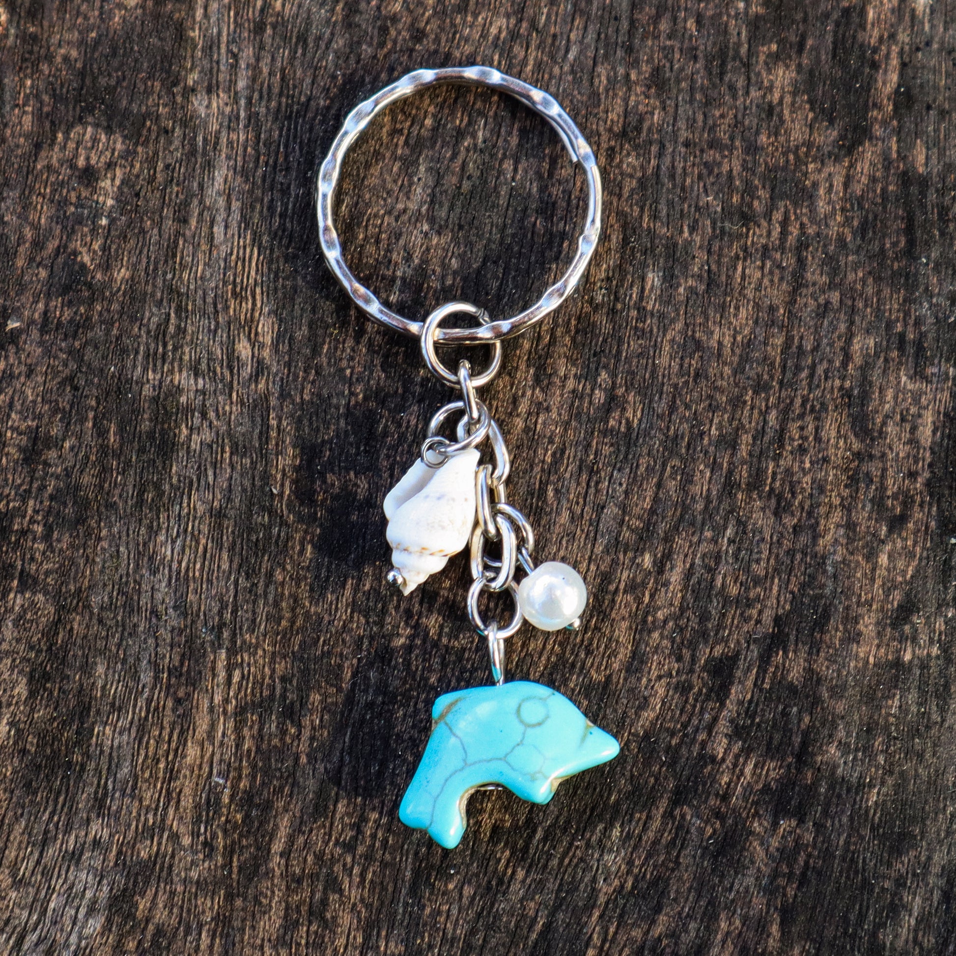 Keychain with blue bear charm, seashell, and pearl on a wooden background