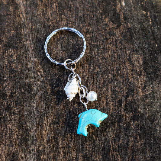 Keychain with a turquoise dolphin charm and shell on a wooden surface