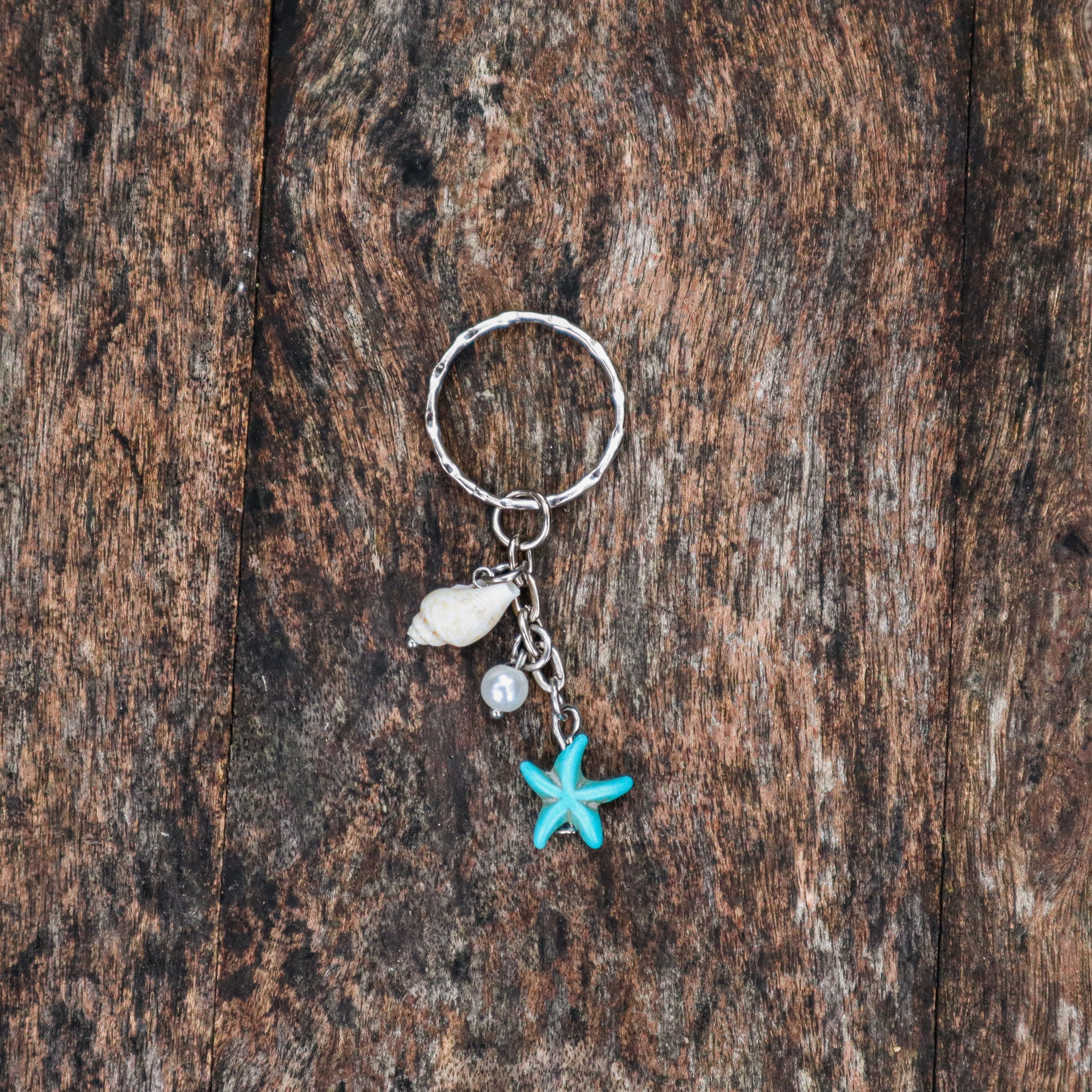 Keychain with starfish and shell charm on a wooden surface