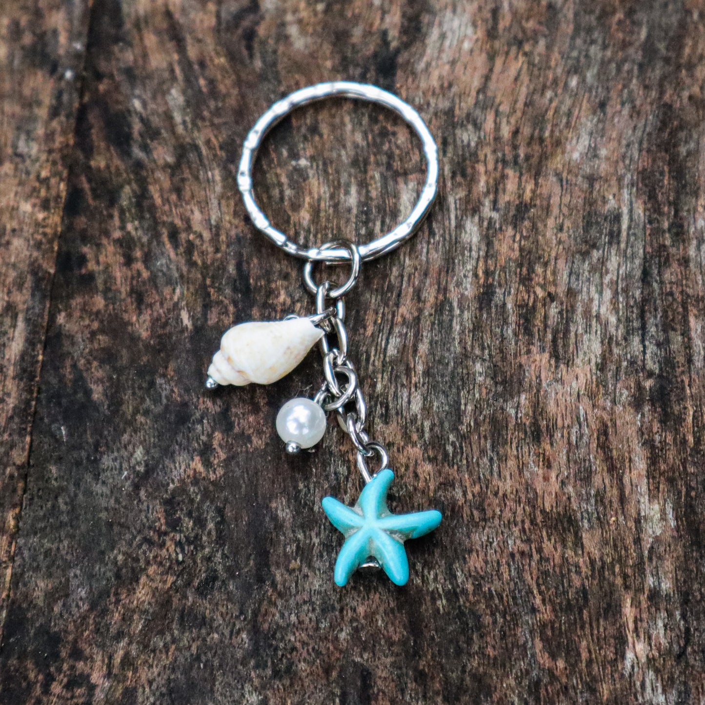 Keychain with starfish, shell, and pearl charm on a wooden surface