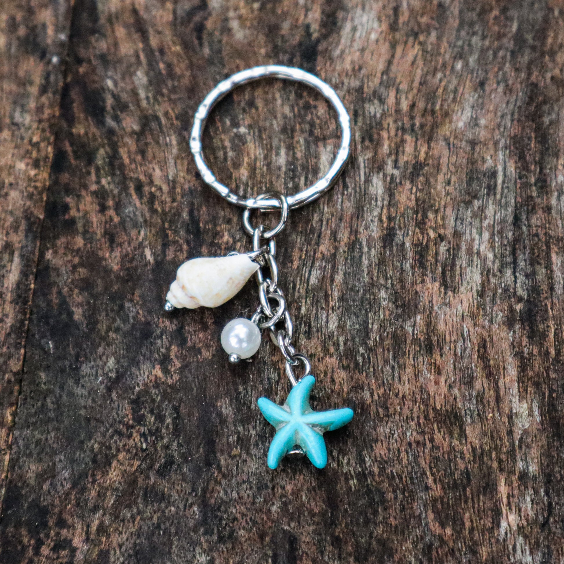Keychain with starfish, shell, and pearl charm on a wooden surface