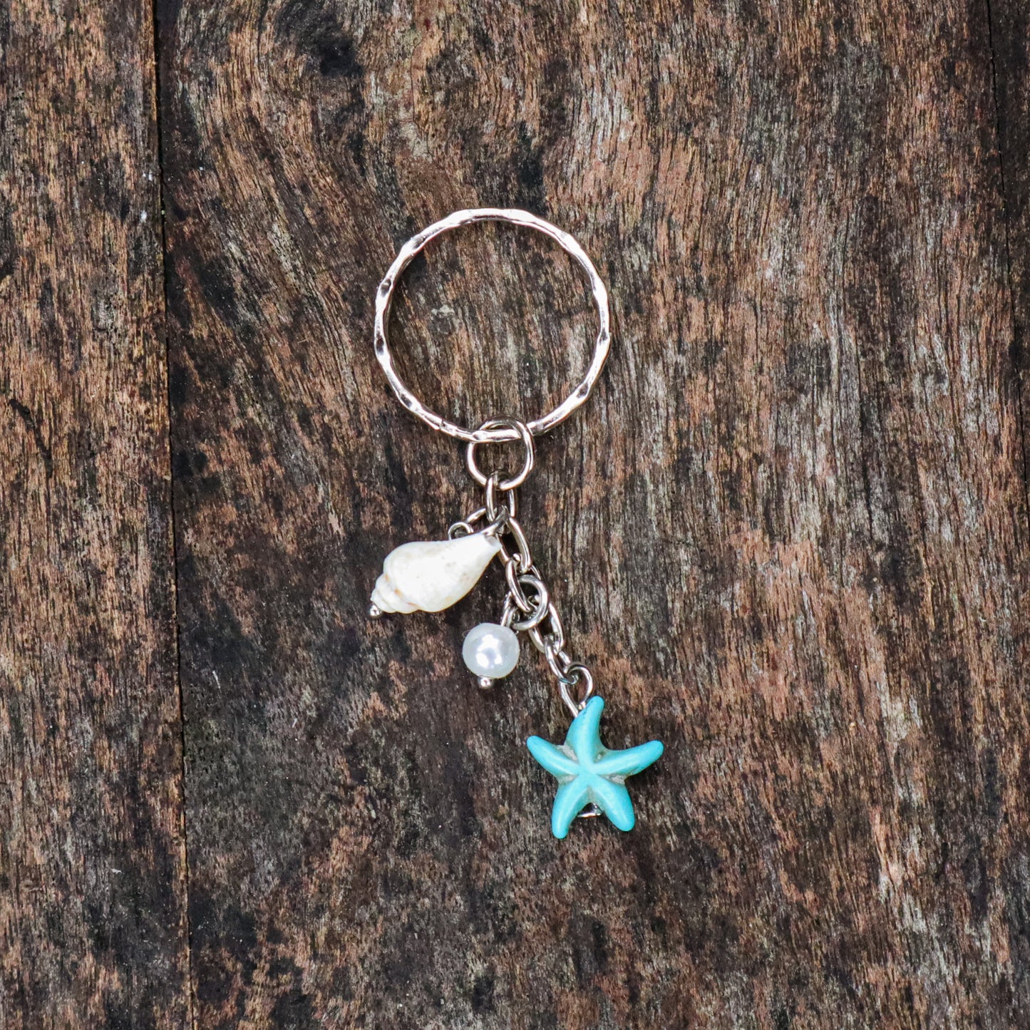 Keychain with starfish, shell, and pearl charm on a wooden surface