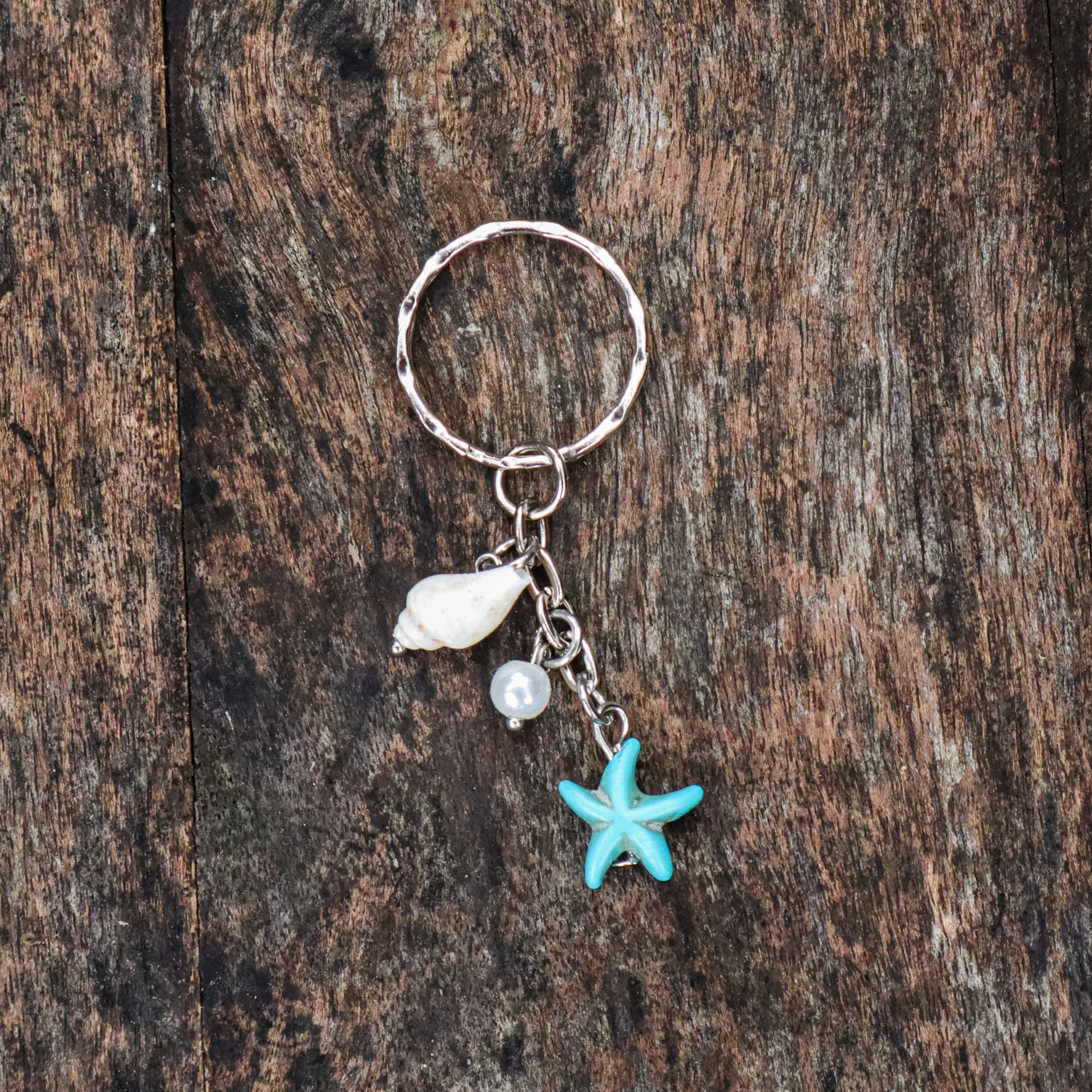 Keychain with starfish, shell, and pearl charm on a wooden surface