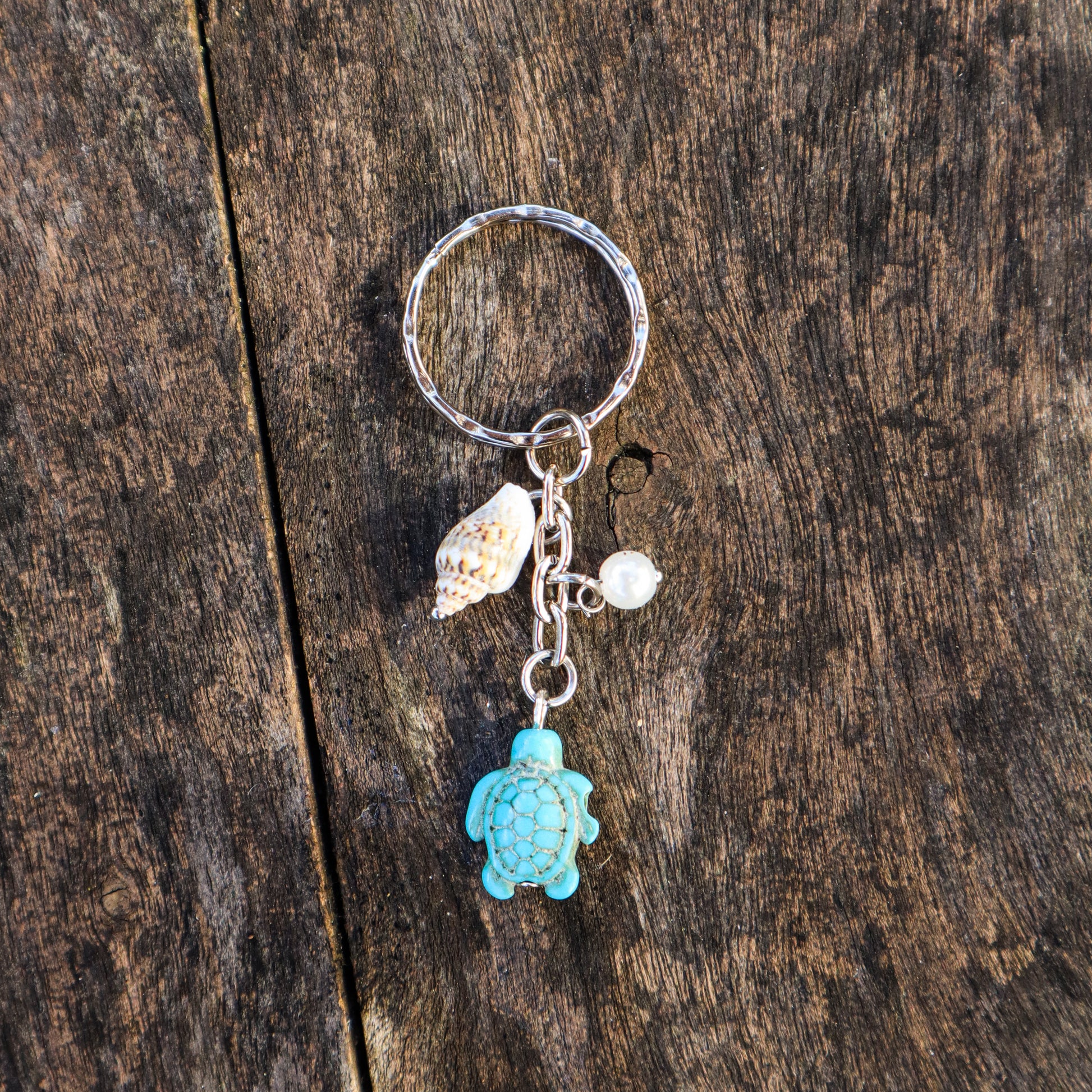 Keychain with turtle charm and shell on a wooden surface