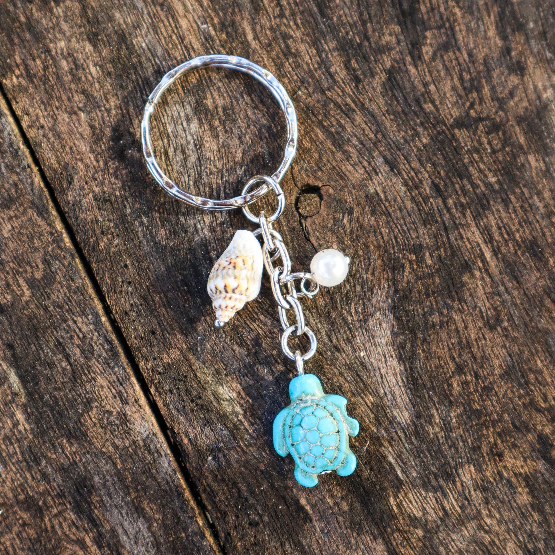 Keychain with turtle charm and shell on a wooden surface