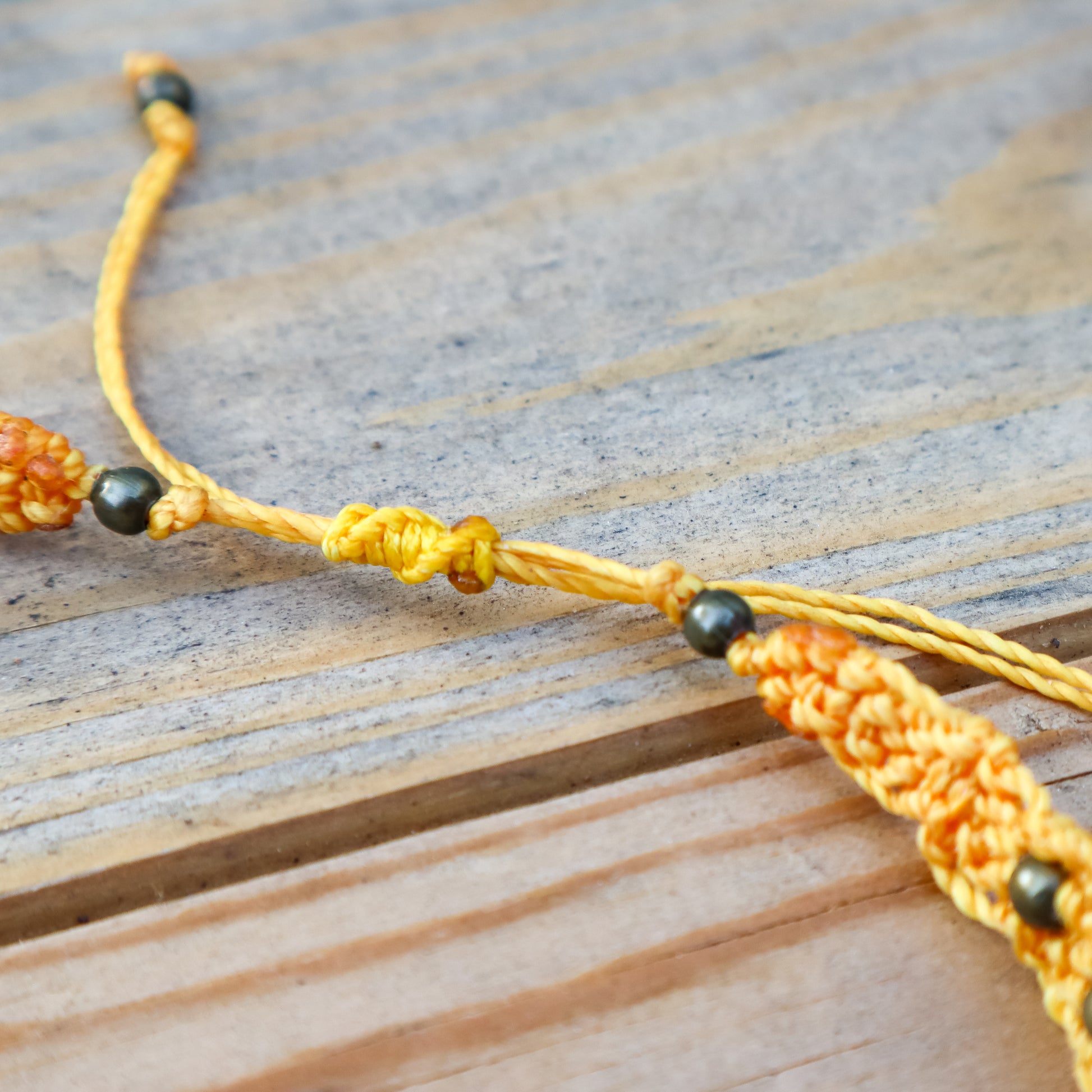 Close-up of a yellow bracelet with bronze beads on a wooden surface